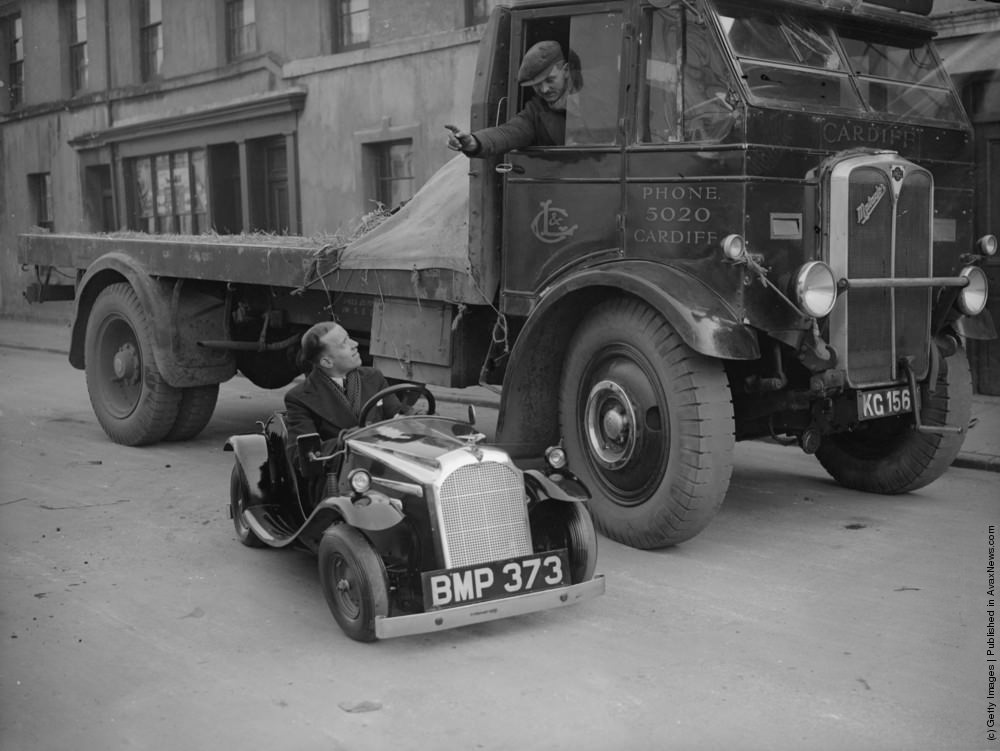 A lorry driver talking to the driver of a midget car in Cardiff. February 1935.