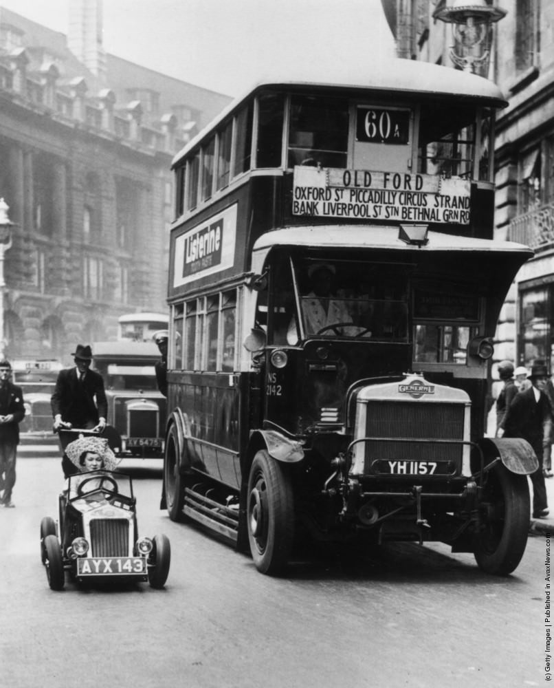 A bus and a midget car in a London street. Circa.