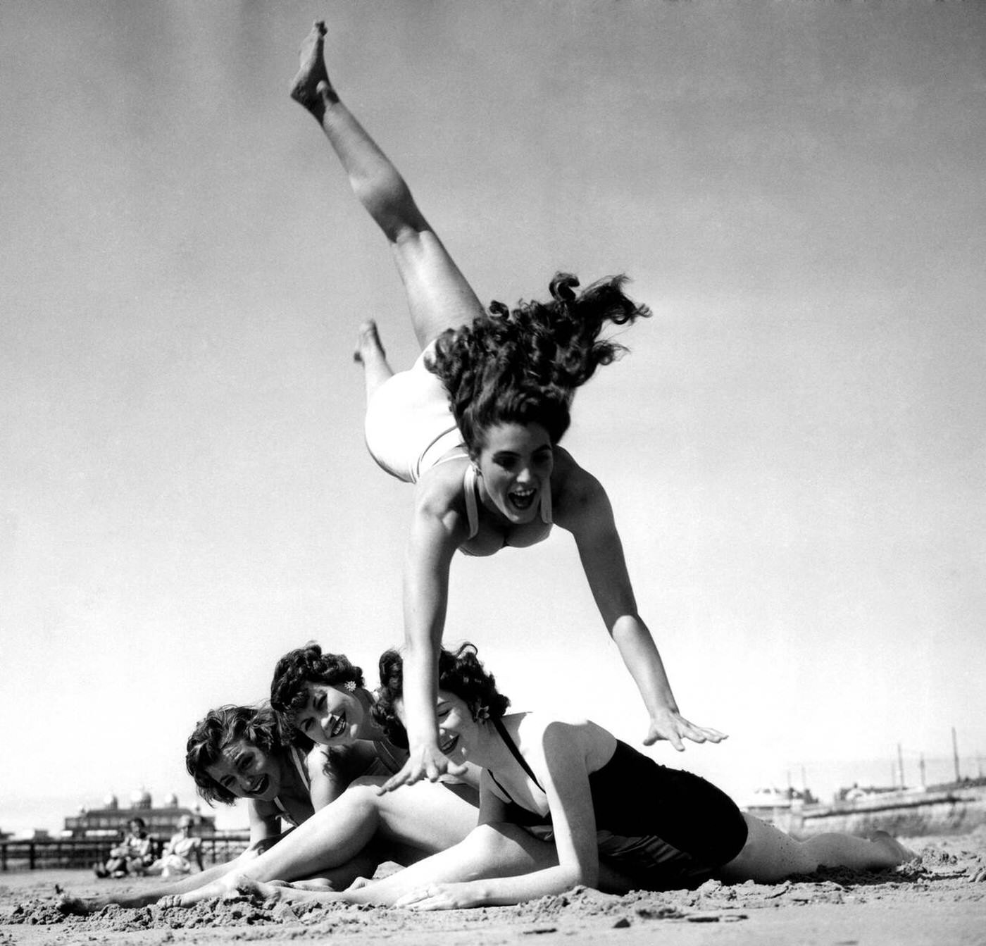 Dancing teacher Hazel Cleaver leaping over friends on a beach.
