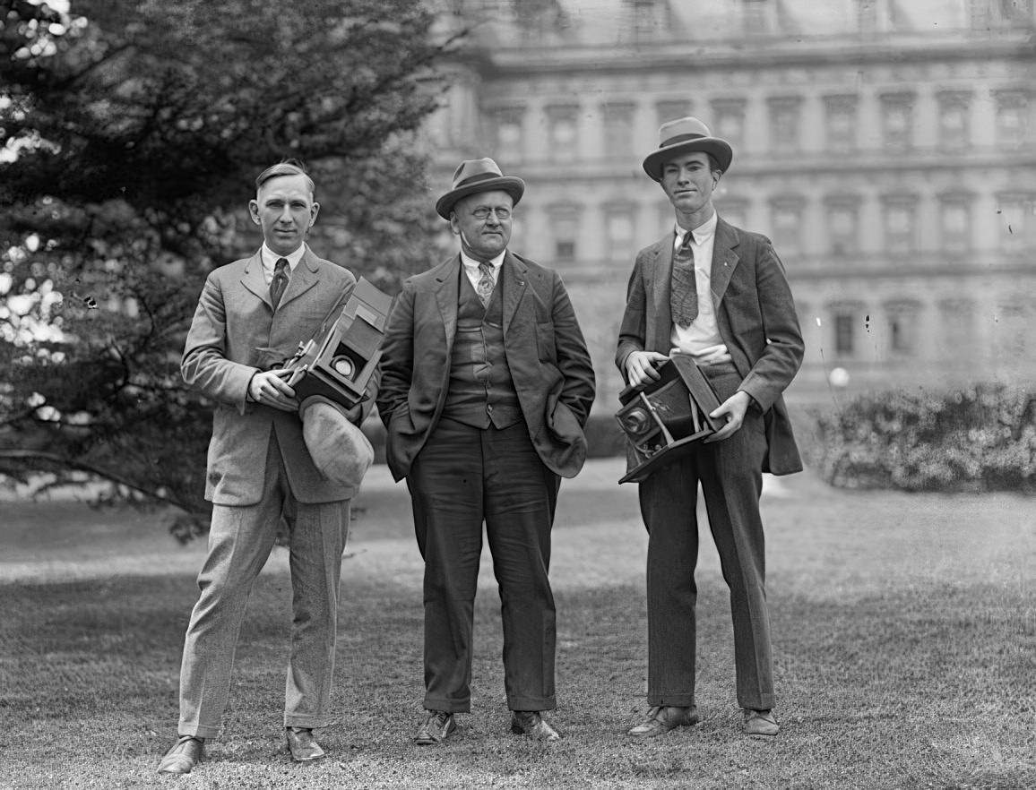 Three guys posing with two cameras in the early 1900s.