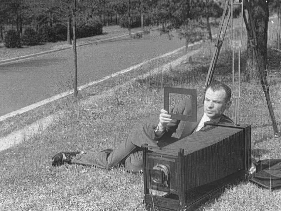 Theodor Horydczak lying on ground with camera in the early 1900s.
