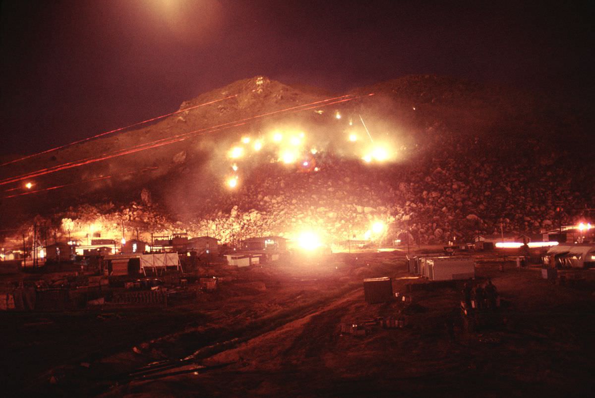 Flares continue to burn as soldiers pepper the hillside with M60 fire.