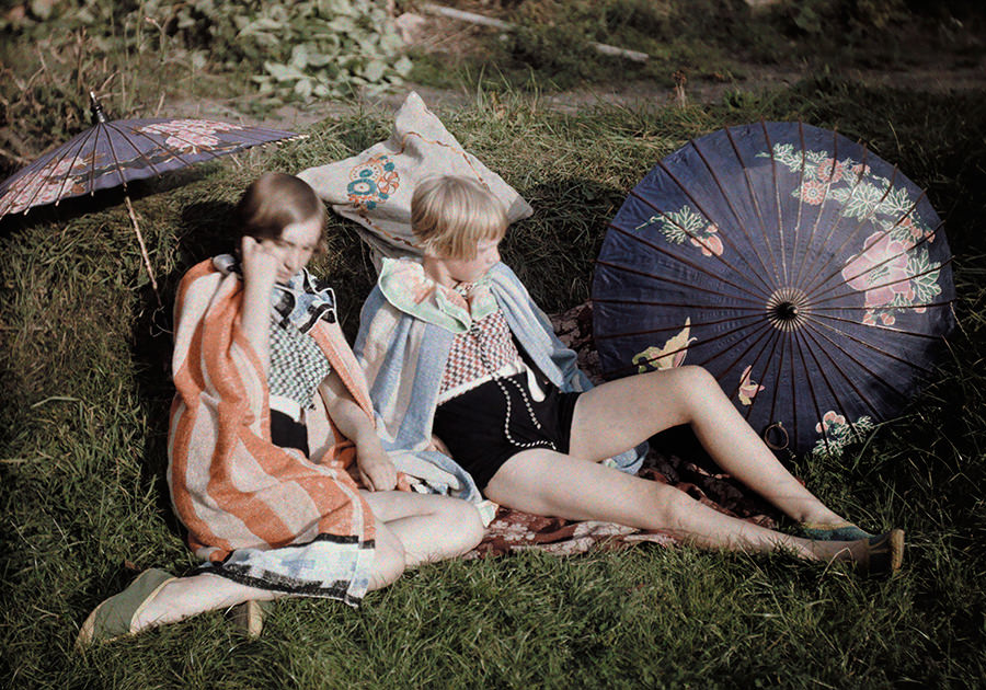 Two young girls enjoy the sun relaxing in their suits and wraps in England, September 1929.
