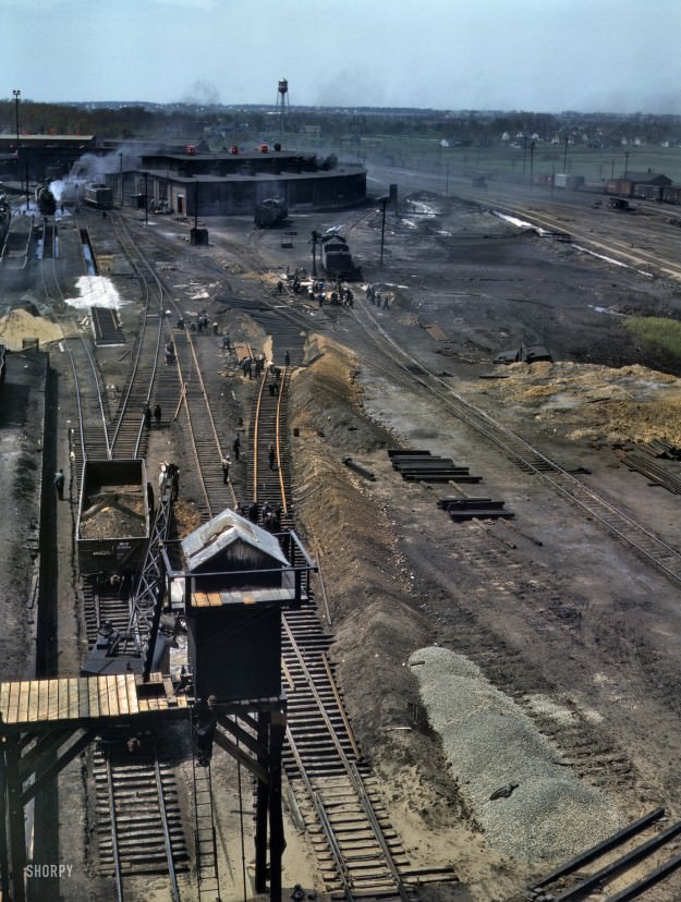 May 1943. Bensenville, Illinois. “Bensenville yard of the Chicago, Milwaukee, St. Paul, and Pacific Railroad. Track repair and work on the cinder pits at the roundhouse.” 4×5 Kodachrome transparency by Jack Delano.
