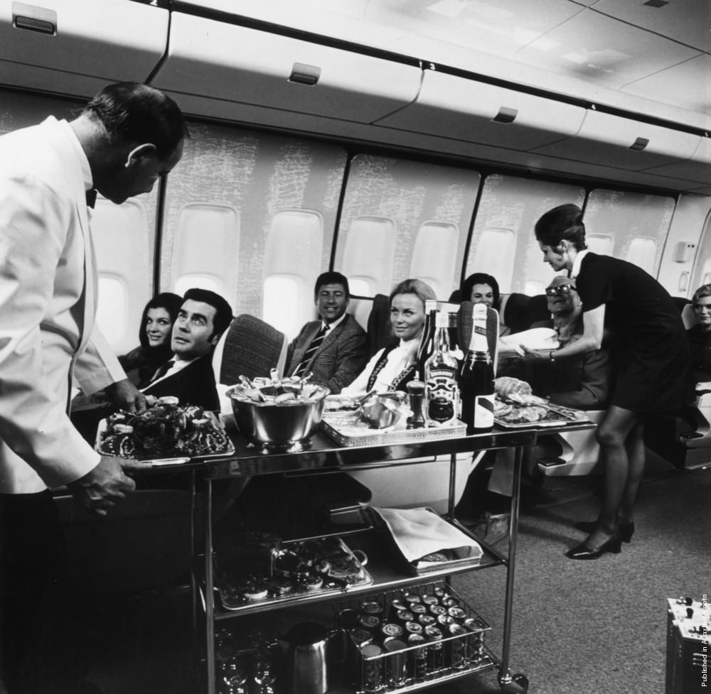 A steward and stewardess serving first-class passengers on a Boeing 747, 1970.