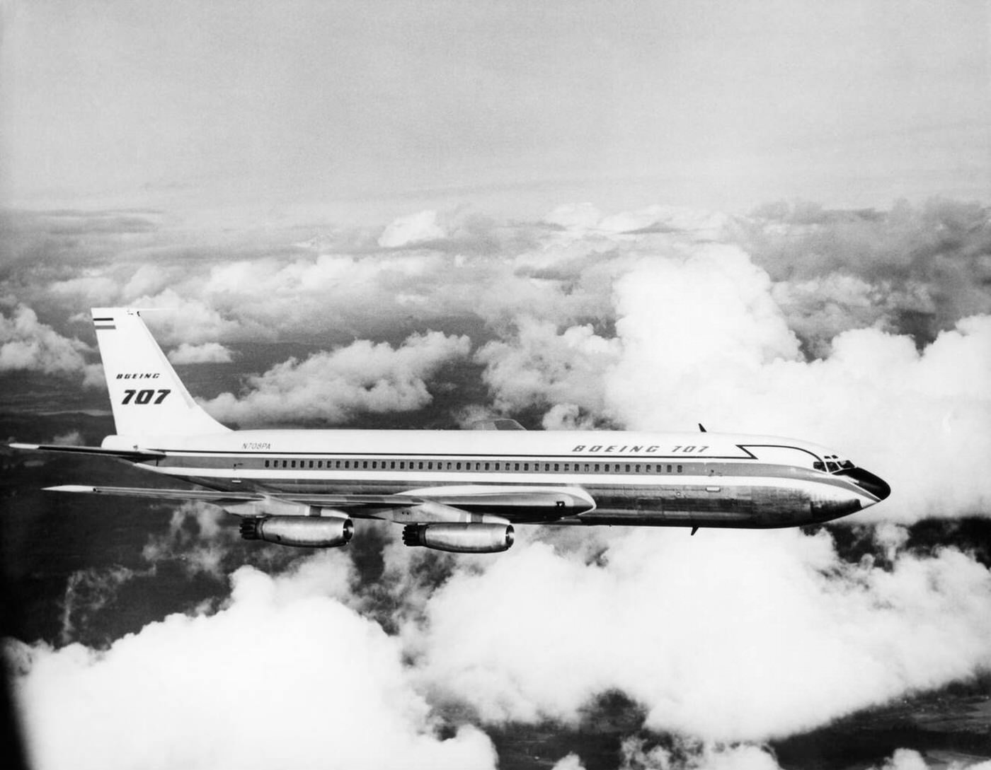 A Boeing 707 passenger jet flying through clouds, 1950s.