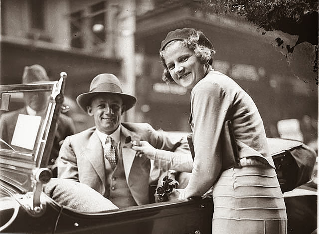 Poppy seller pins the flower on cricketer Don Bradman's lapel outside the State Theatre, Sydney, 1930s.