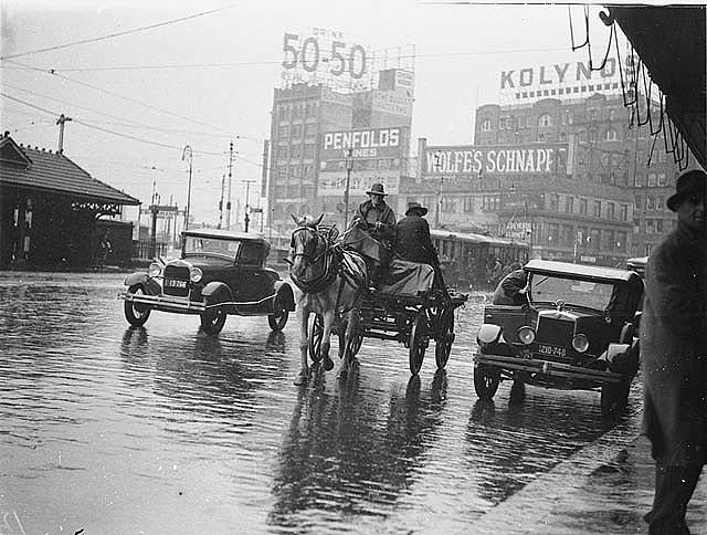 A dray, a Ford, and a Morris Oxford Roadster in summer rain, Railway Square, Sydney, 1935.