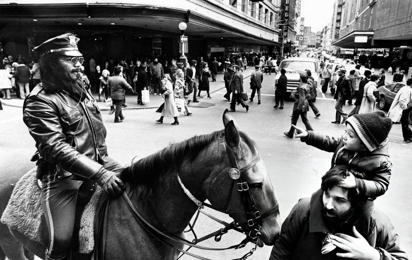 Tom Germelli, Jr., and his dad stop their Christmas shopping to look at a Boston Police Officer in Boston, 1977.