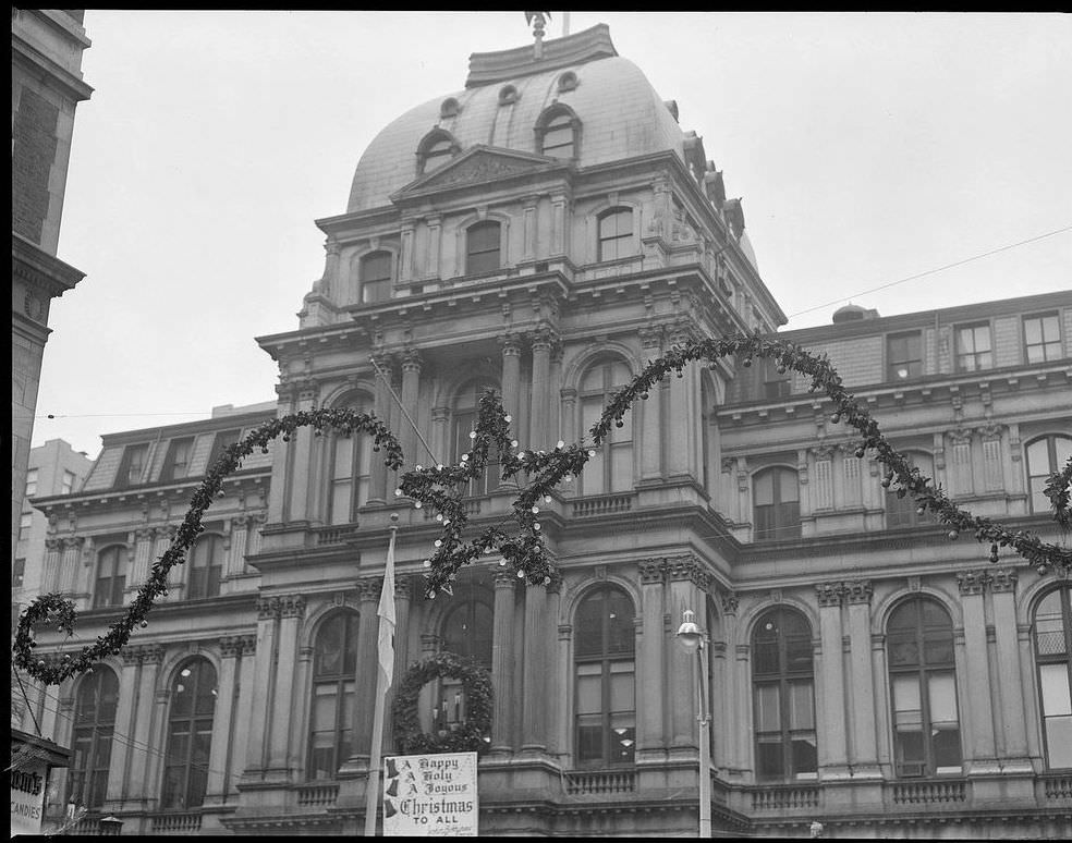 The sign on another entrance to Boston City Hall called for "A Happy, A Holy, A Joyous Christmas To All," 1954.