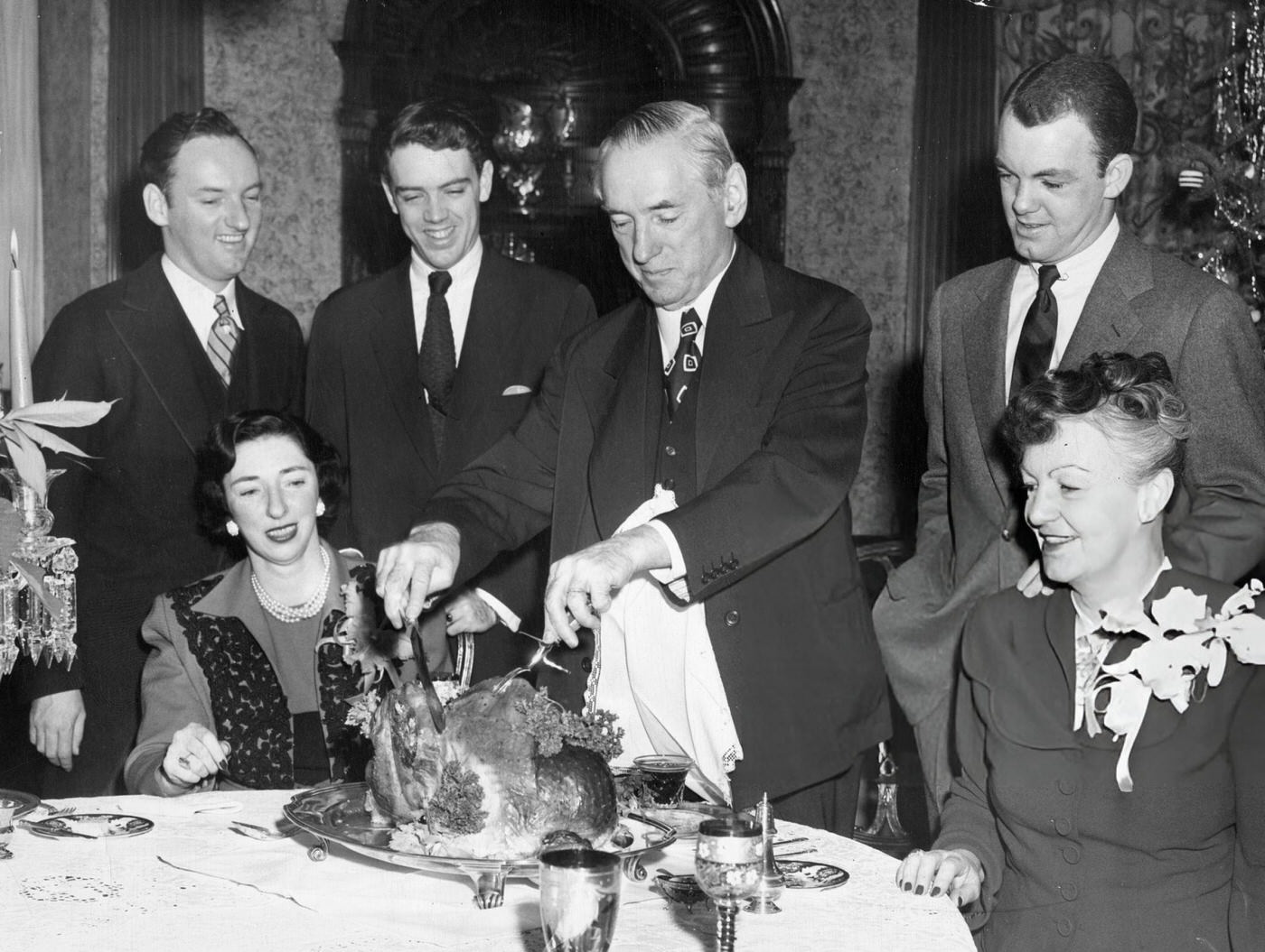The Curley family surrounds Mayor James Michael Curley as he cuts the Christmas turkey at home in Boston, 1948.