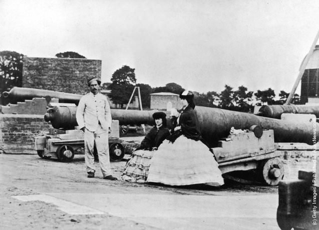 A soldier and two women posing next to cannons during the Crimean War, 1850s.