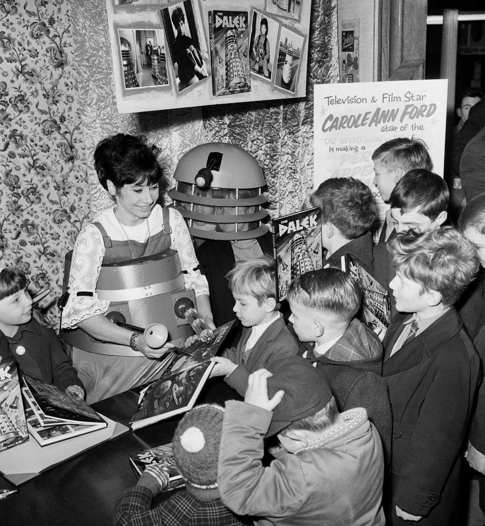 Carole Ann Ford autographs a copy of the Dalek Book for children and demonstrates a child-powered Dalek toy at Gamage Store, London, 1964.