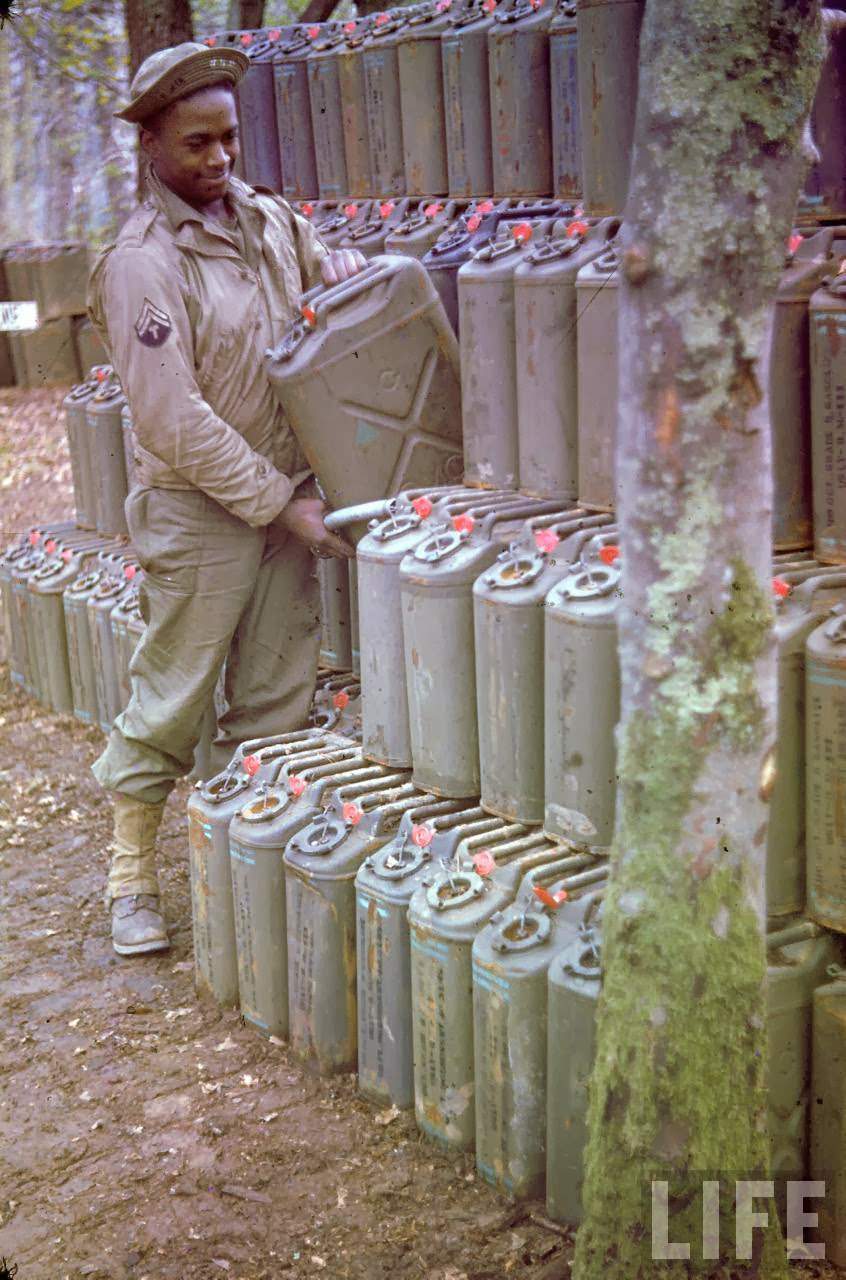 African American soldier piling up gas cans in preparation for the upcoming D-Day invasion of France.