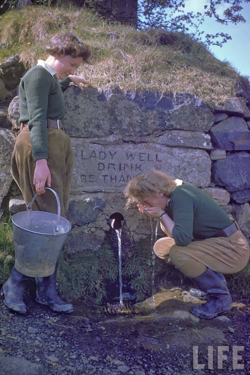 Pair of English Land Army girls taking a drink from a roadside well during WWII.