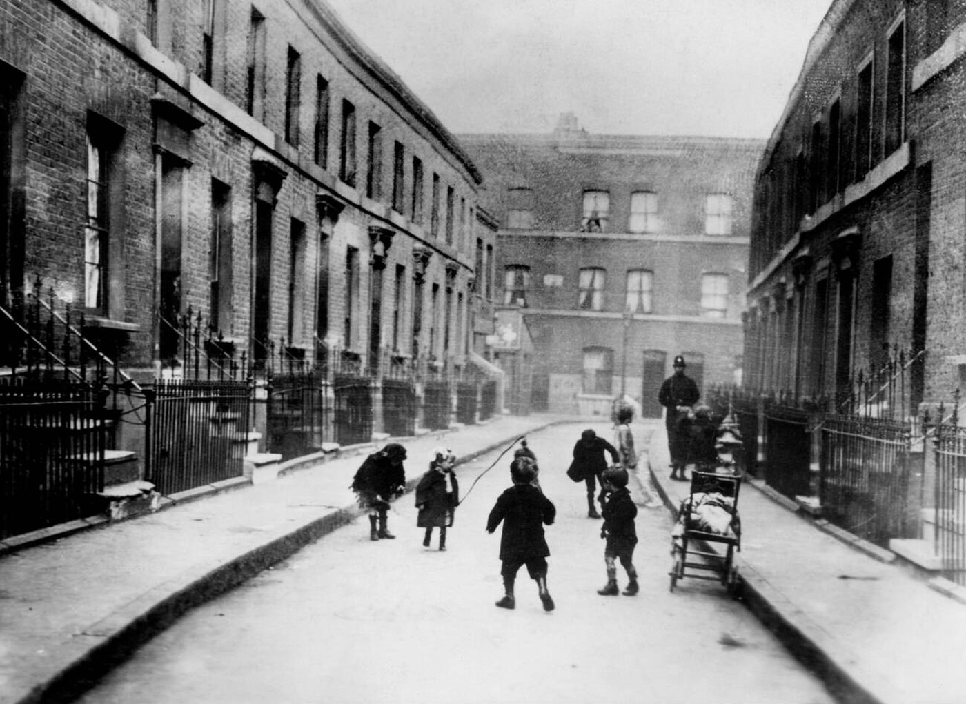 Children playing outside their slum dwellings in Laursa Place, Shoreditch, London, 1920.