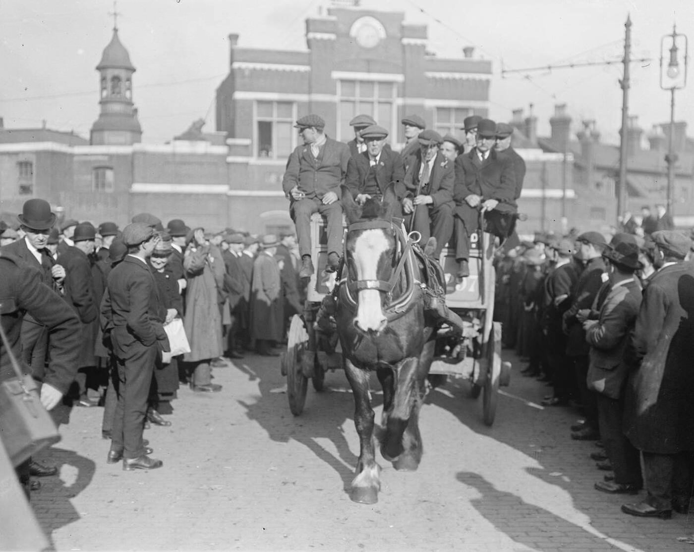 March of ex-soldiers from Woolwich Arsenal to see the Premier with wounded men leaving the Arsenal in a cart, 1920.