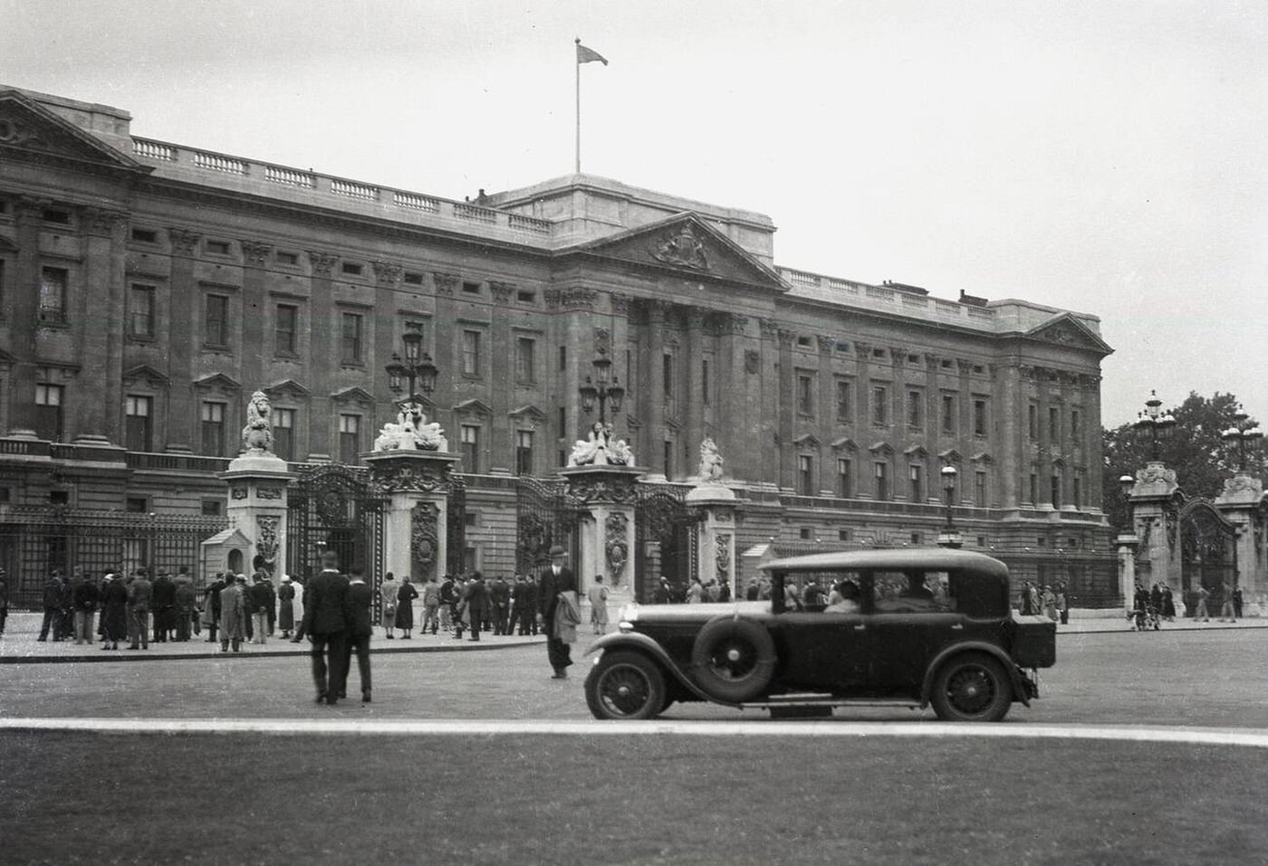 A four-door motorcar parked on the Mall opposite Buckingham Palace, London, 1920s.