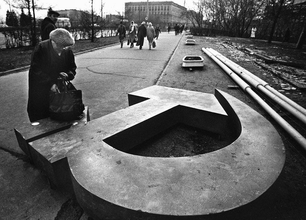 A woman reaches into her bag near a fallen Soviet hammer-and-sickle on a Moscow street, 1991.
