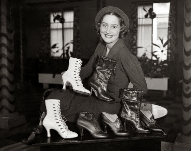 Shoes galore! A model sits behind a stylish display of boots in 1934.
