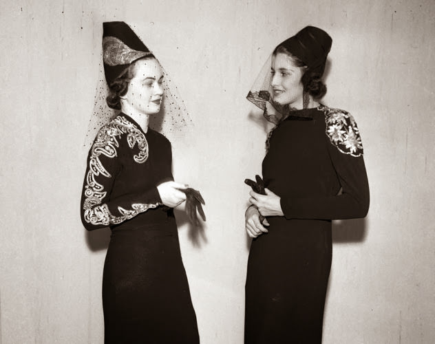 That's some interesting headwear! Two models wear hats with embroidered veils at a 1937 fashion show.