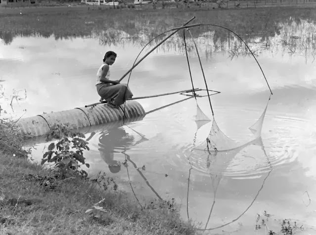 A woman fishing in a residential section of Vientiane, the capital of Laos, 1961.
