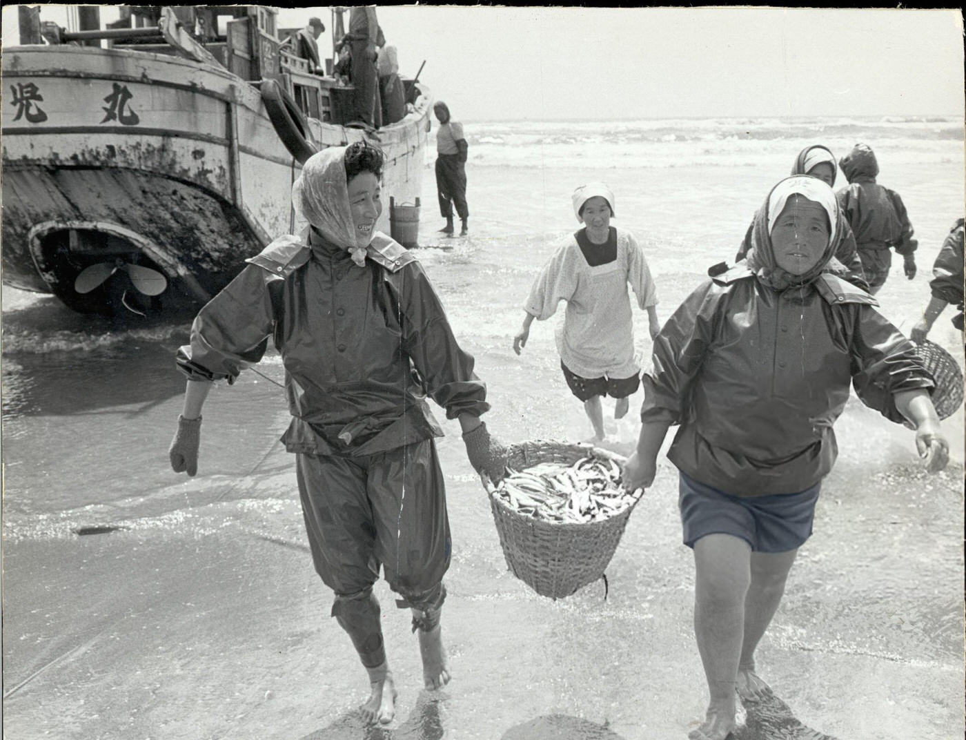 Women fishers carrying a basket of fish after a fishing vessel returns to the beach near Tokyo.