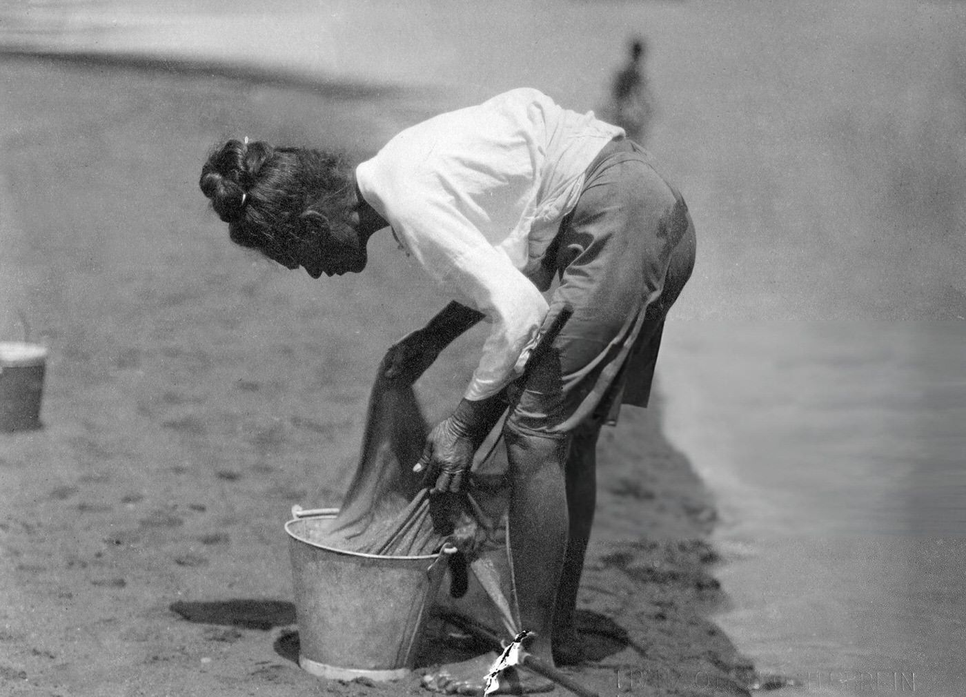 Fisherwoman emptying her fishing net in Hawaii, 1910.