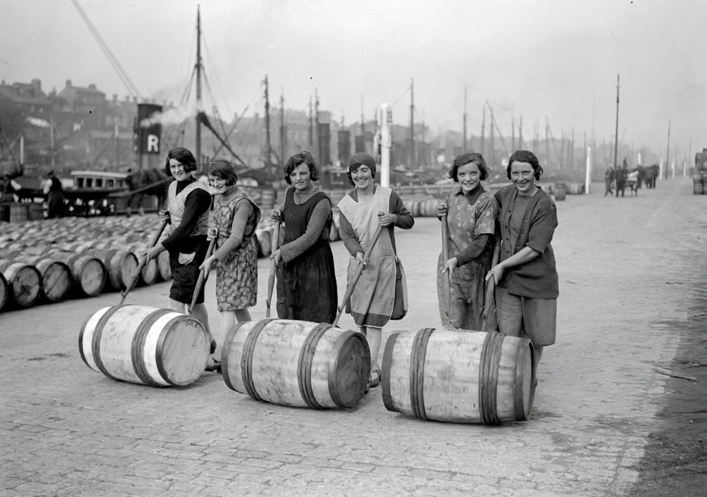 Yarmouth fisher-girls pushing barrels of herring along the quayside, 1929.