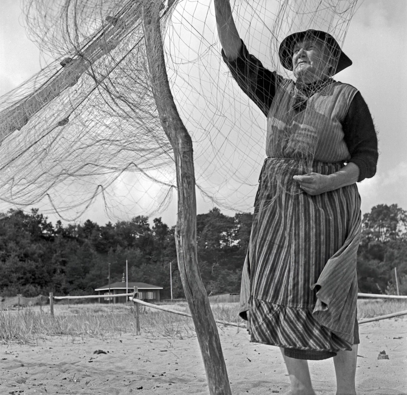 A fisherwoman assorting his net at Rositten on the Baltic Sea in East Prussia, 1930s.