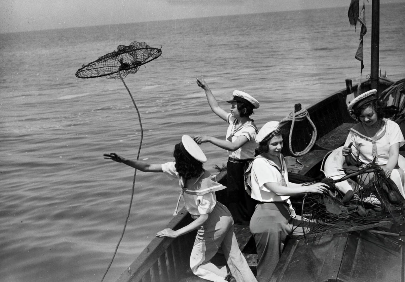 An all-female crew casting a net from their yacht off Cowes in the Isle Of Wight, 1940.