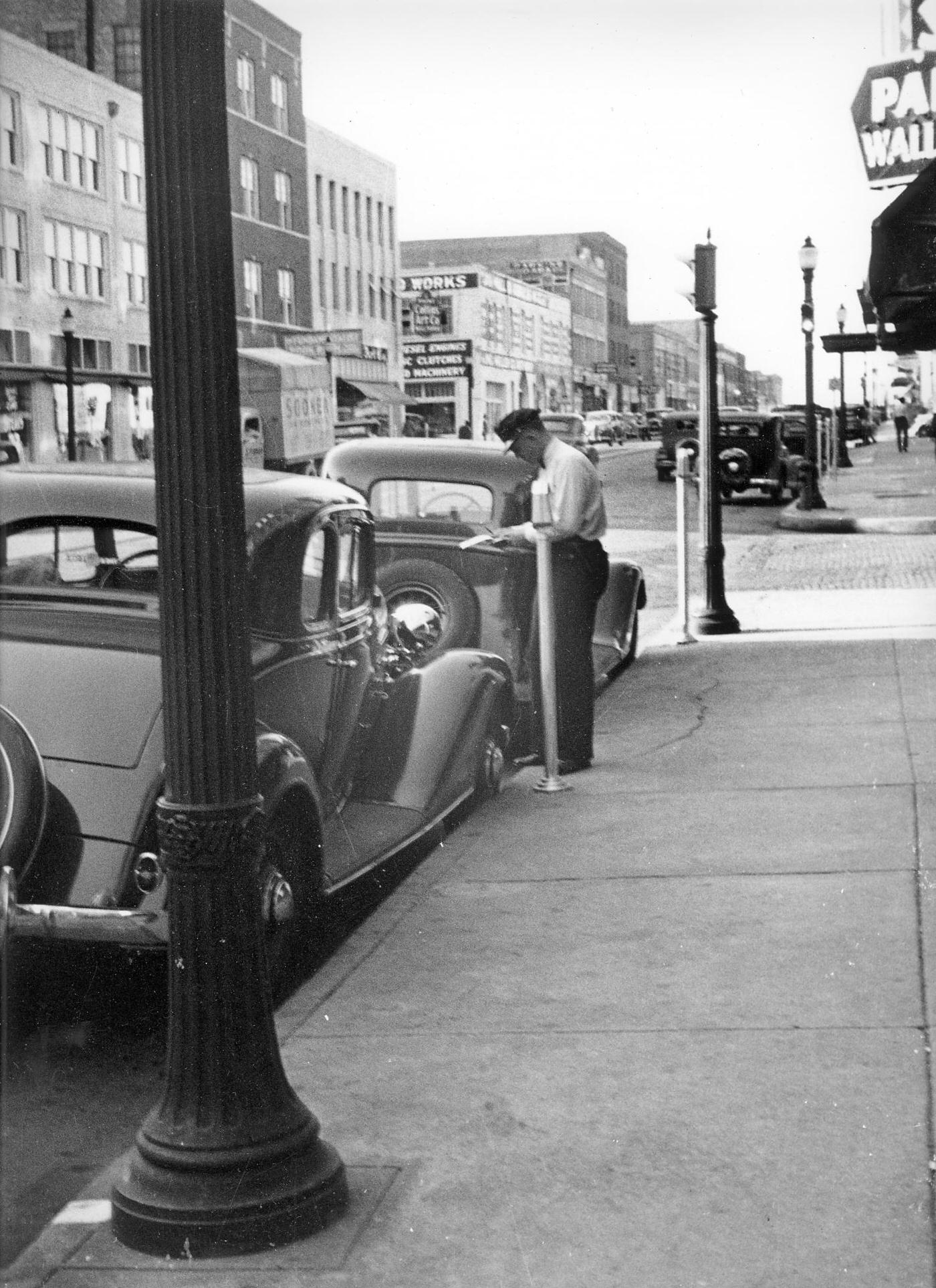 A police officer writing a parking ticket, 1930s.