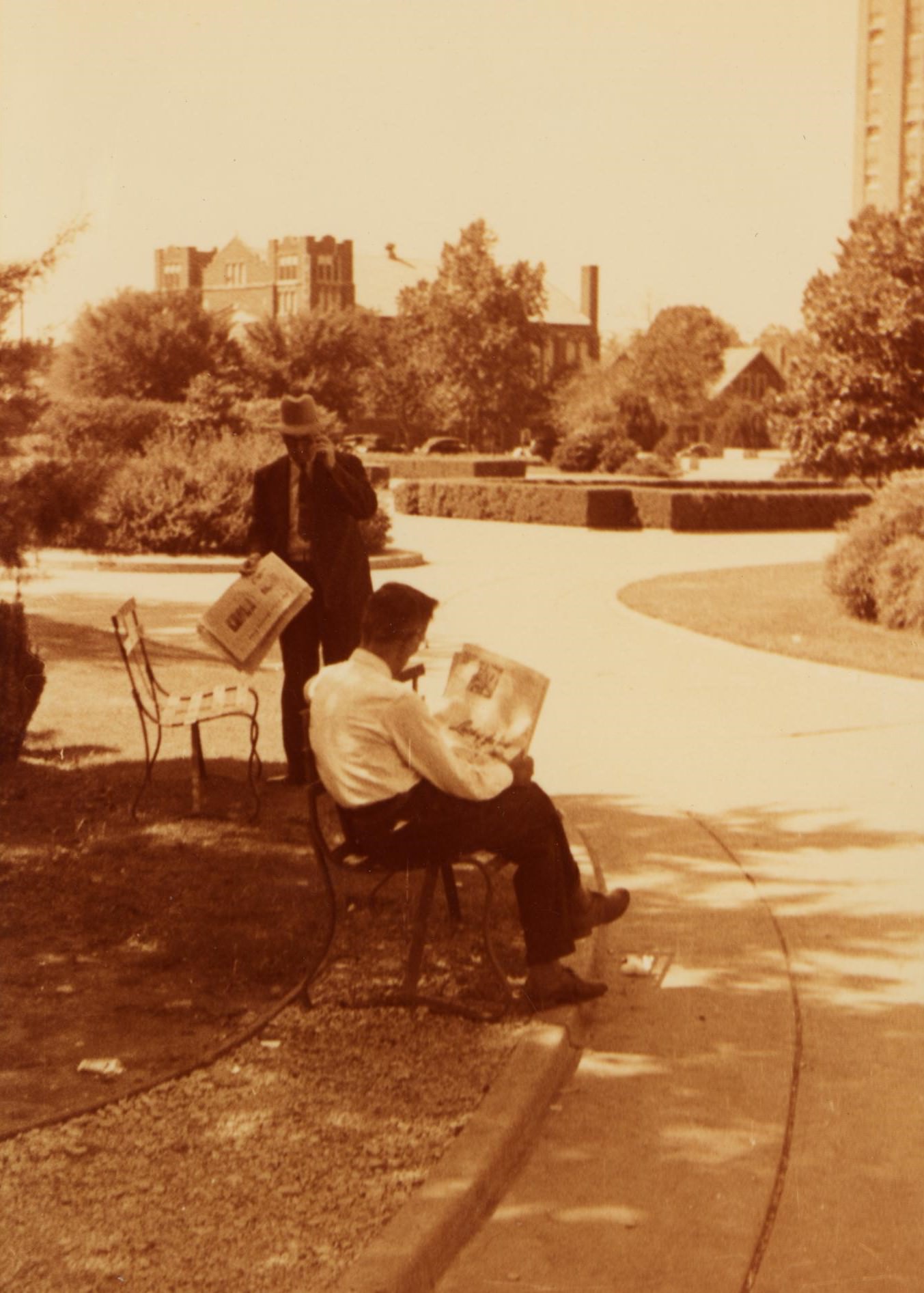 Two men reading a newspaper in a park, 1930s.