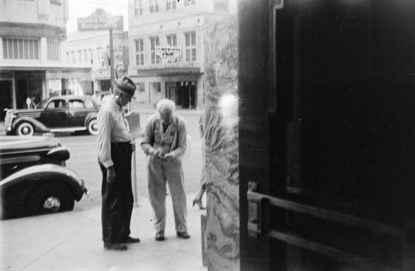 Two elderly men talking on a sidewalk in downtown Fort Worth, Texas, 1937.