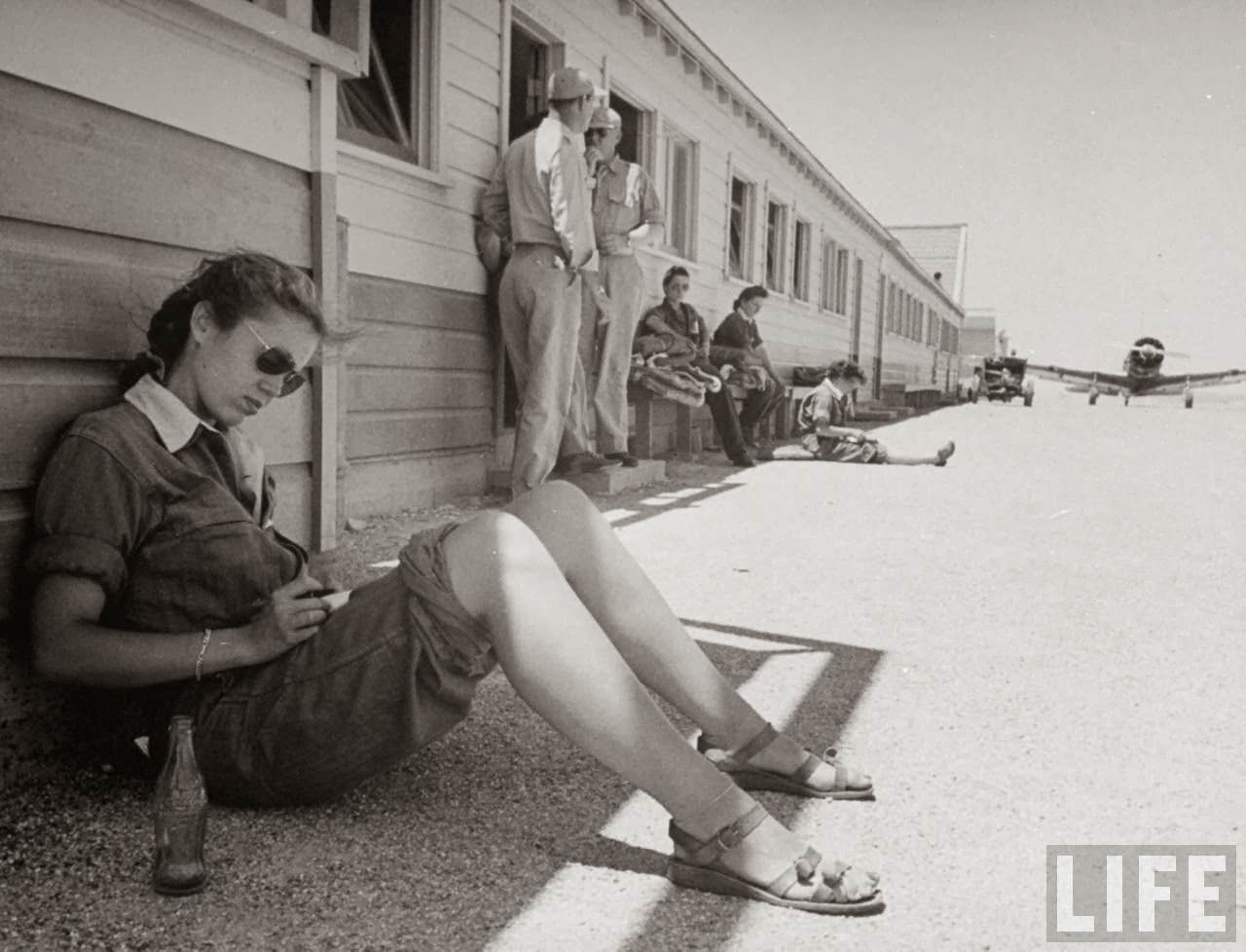Madge Rutherford, pilot trainee in the Women's Flying Training Detachment, writing letter home w. a finished Coca Cola by her side as she leans against barrack while waiting for her flight period on basic line, at Avenger Field.