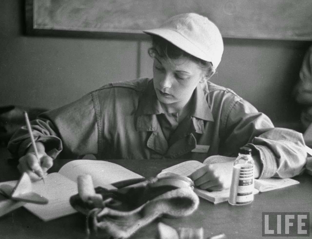 Phyliss Jarman, pilot trainee in the Women's Flying Training Detachment, wearing her favorite white baseball cap, writing up a report in workbook during training to fly for the Women's Auxilary Ferrying Squadron, at Avenger Field.