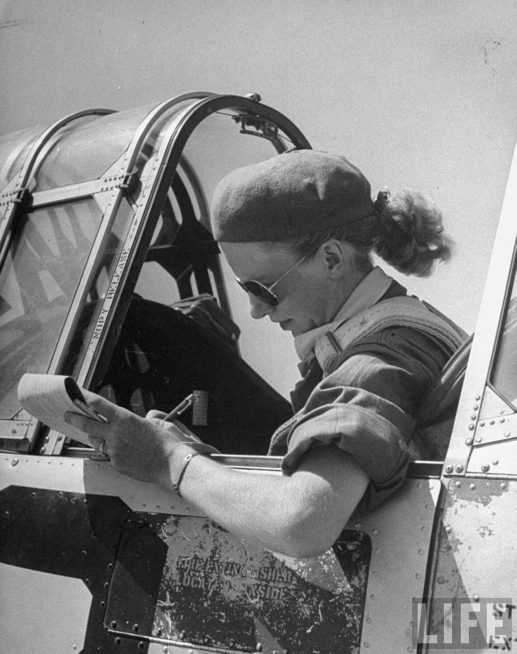 Jean Pearson, pilot trainee in Women's Flying Training Detachment to later join the all-civilian Women's Auxiliary Ferrying Squadron, using a beret & a ribbon-tied hair knot to keep hair fr. flying, in cockpit of trainer before takeoff at Avenger Field.