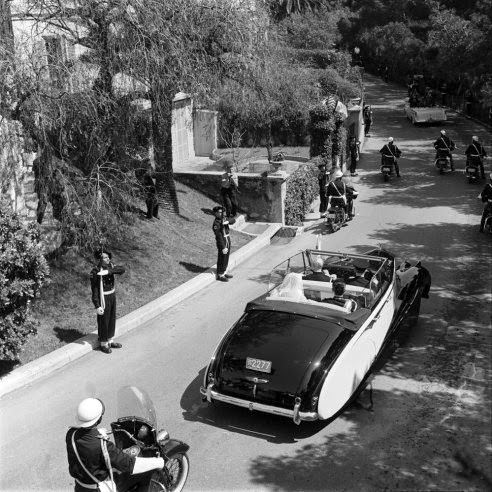 Princess Grace and Prince Rainier III, newlyweds, are whisked away in a Rolls Royce convertible, April 1956