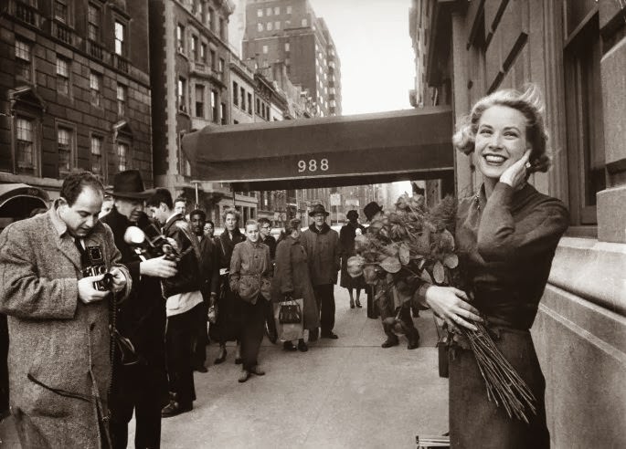 Smiling in a brisk March wind and surrounded by photographers and fans, Grace Kelly poses just off of Fifth Avenue in New York, 1956