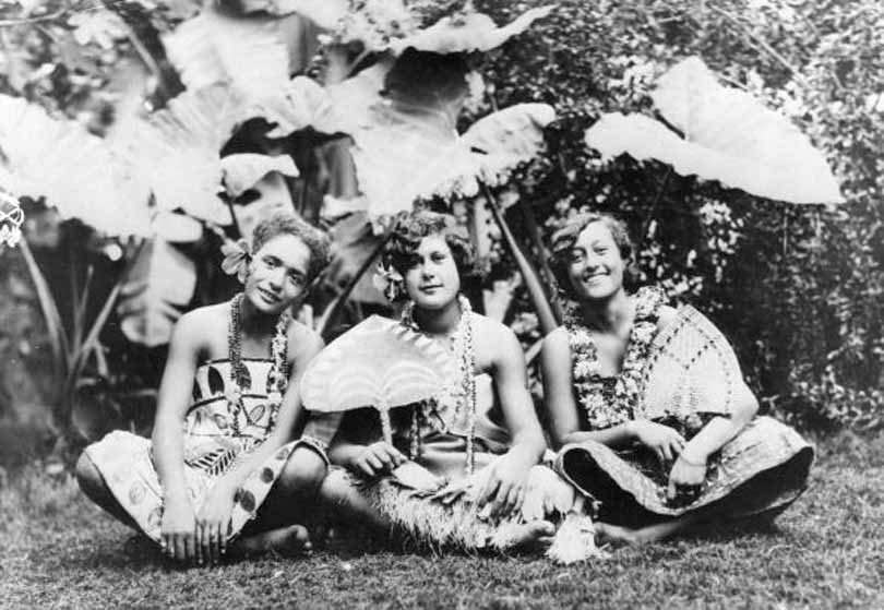 A group of Hawaiian girls sit against a tropical background, 1932.