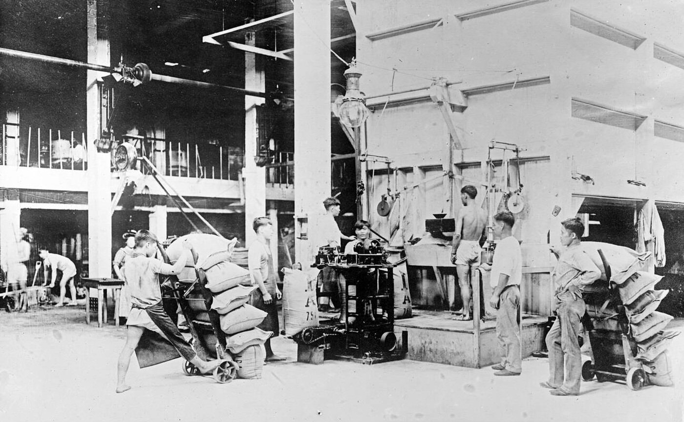Filling sacks of raw sugar at Plantation mill, Hawaiian Islands, 1910s.