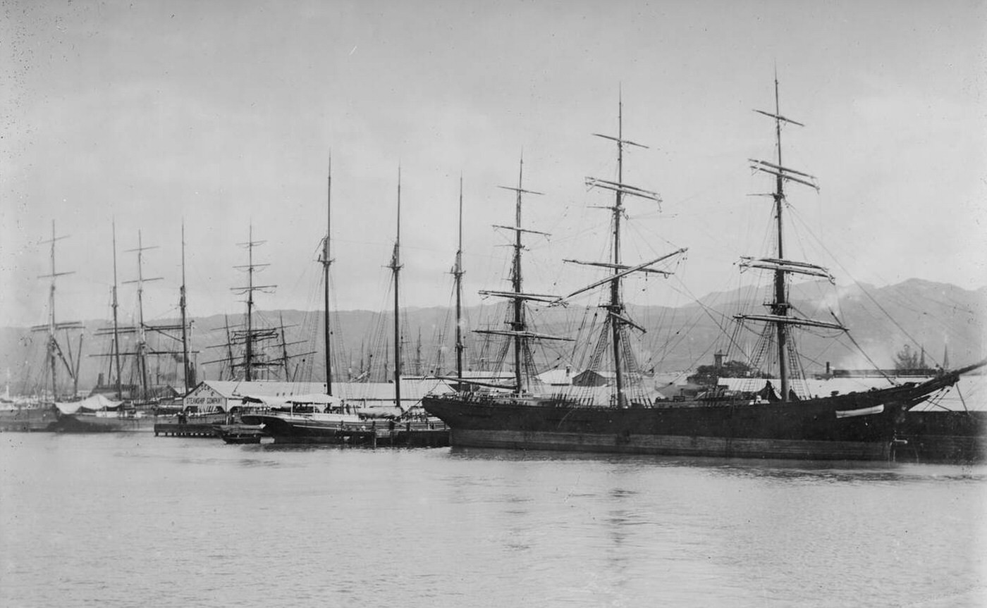 Sailing vessels docked at the wharf in Honolulu Harbor, 1890s.