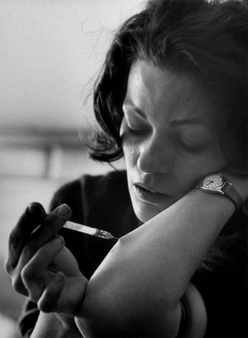 Karen using hypodermic needle on an eyedropper which addict call a "spike" to shoot heroin into vein in her arm.