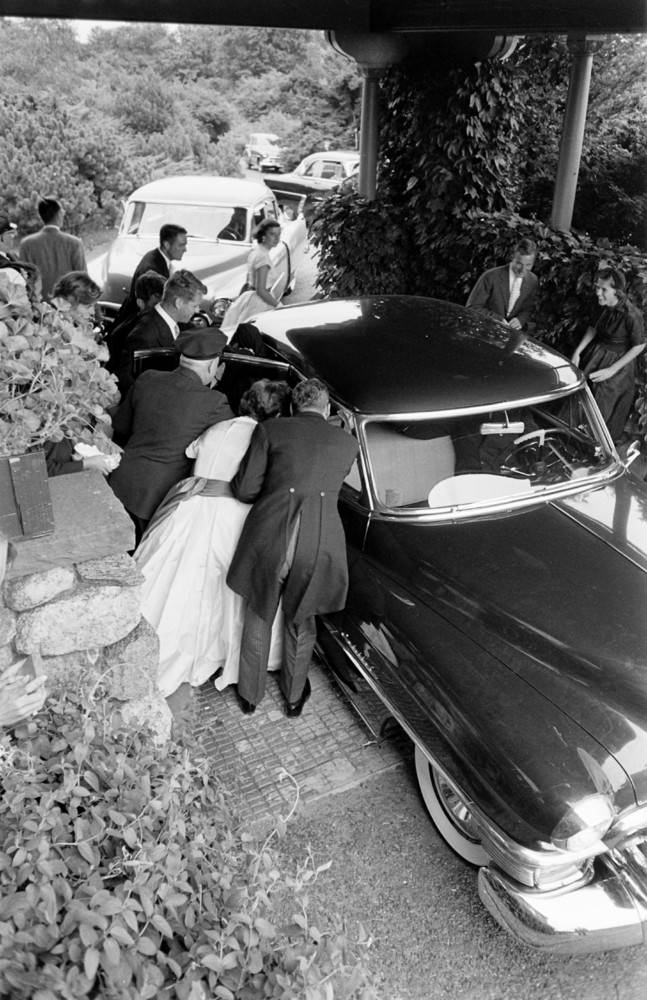 Well-wishers gather around the car carrying the newlyweds to their reception, Newport, Rhode Island, 1953.