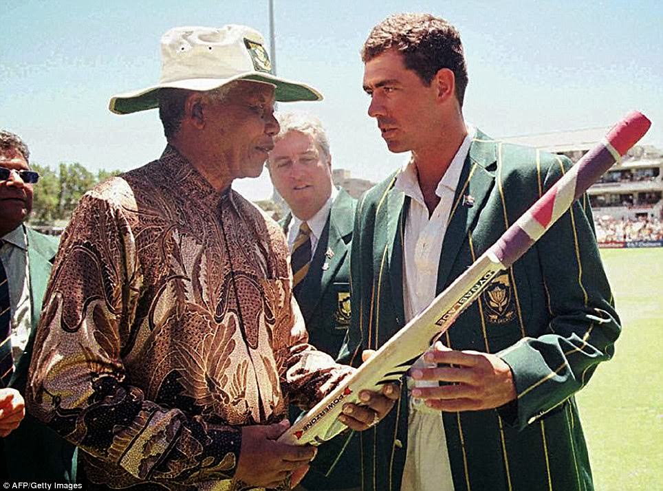 South African President Nelson Mandela receives a cricket bat from the South African Cricket captain, Hansie Cronje, during the lunch break on the third day of the Second Test between South Africa and India at Newlands on January 4, 1997.