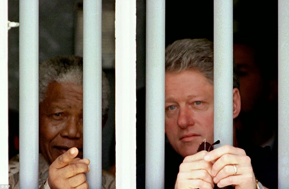 In this March 27, 1998 file photo, South African President Nelson Mandela, left, and U.S. President Bill Clinton peer through the bars of prison cell No. 5, the cramped, gray cell where Mandela was jailed.