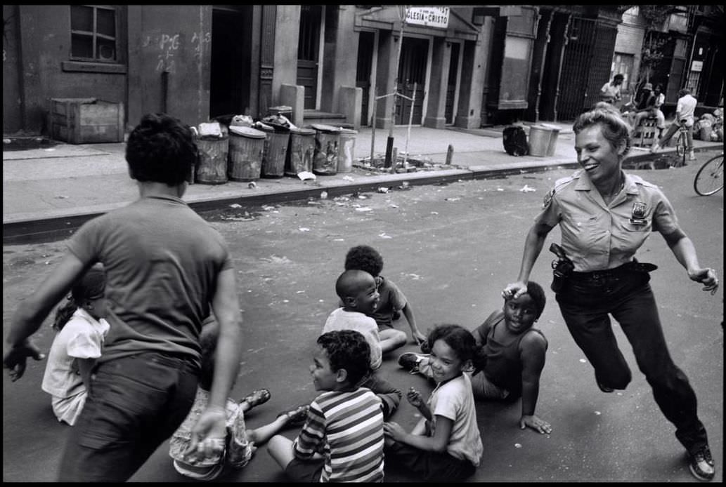 Police officer playing with children in Harlem, 1978.