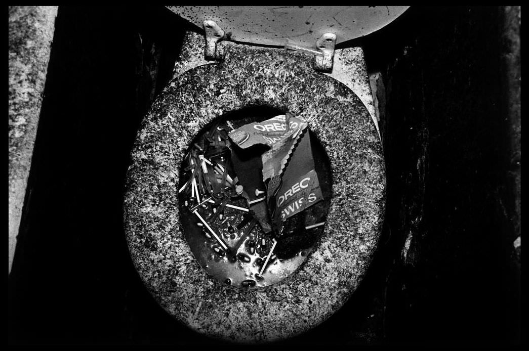 Toilet clogged with gelatin capsules and syringes, 1979.