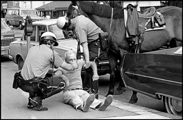 Mounted police raise a fallen man in the street, 1972.