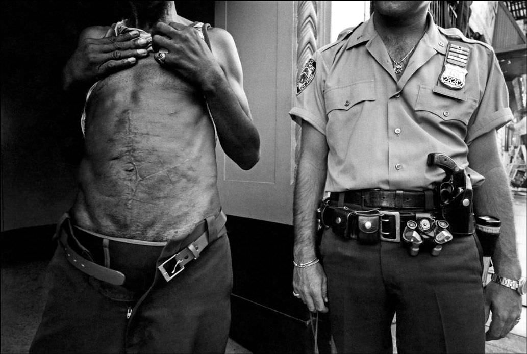 The district shows traces of drug dealers' stab wounds; police walk around with two guns, 1978.
